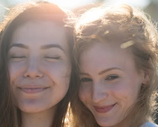 Dos jóvenes sonriendo, abrazadas